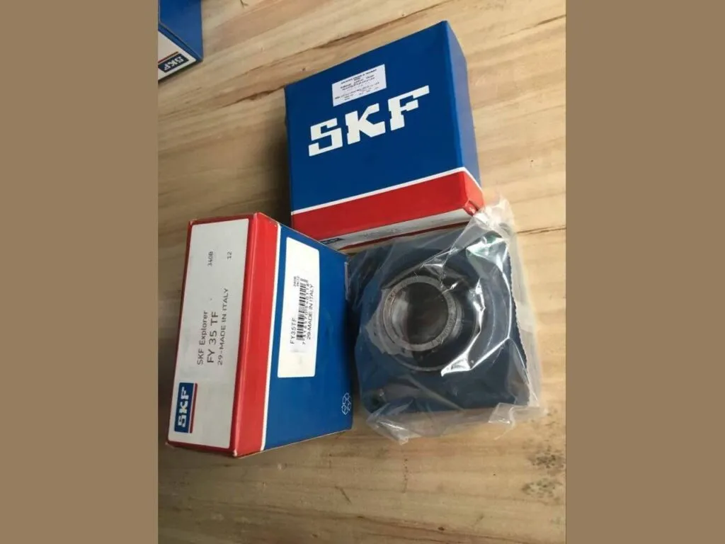 Gối đỡ SKF SY, FY, FYJ, FYTB: Hộp SKF và gối đỡ vuông bọc túi nhựa trên mặt bàn gỗ