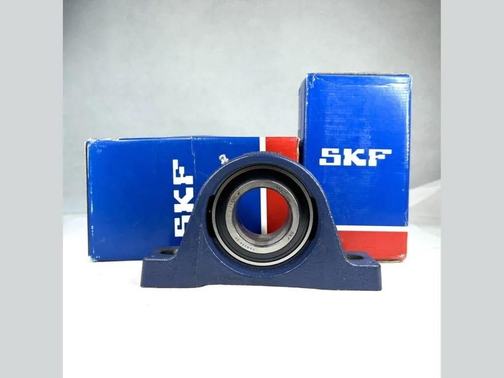 Gối đỡ UCP: Gối đỡ UCP thân xanh đậm đặt trước hai hộp SKF