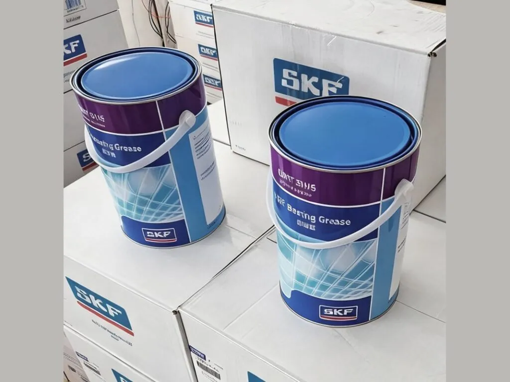 Mỡ SKF LGMT 2 và LGMT 3: Hai xô mỡ SKF có quai xách, nắp xanh đặt trên thùng giấy