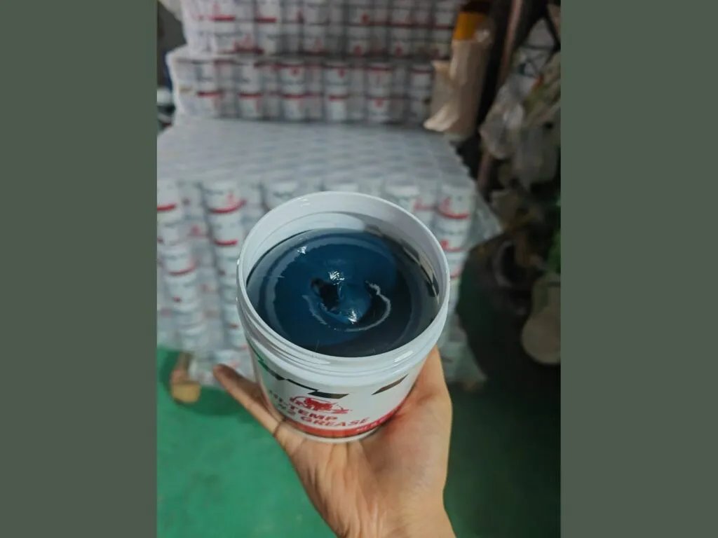 Mỡ SKF LGWA 2: Tay cầm xô mỡ xanh đậm mở nắp, kho hàng phía sau